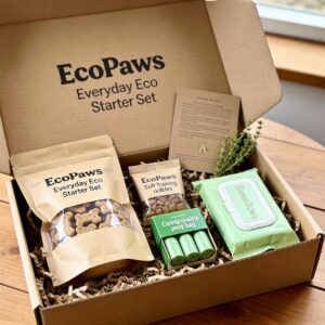 EcoPaws Everyday Eco Starter Set gift box open on a wooden table, showing eco treats, poop bags and grooming wipes nestled in recycled paper